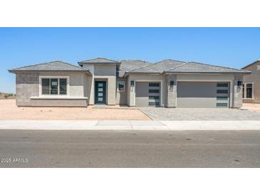 Contemporary home featuring a three-car garage, modern door, and stone accents at 18716 N 269Th Ln, Buckeye, AZ 85396