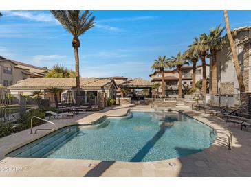 Resort-style swimming pool with lounge seating, umbrellas, and a covered outdoor grilling area at 2025 E Campbell Ave # 114, Phoenix, AZ 85016