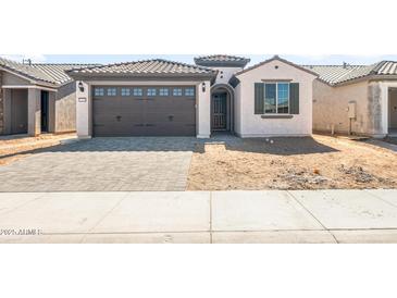 Charming single-story home with a well-manicured lawn and a two-car garage with brick paved driveway at 21296 N 270Th Dr, Buckeye, AZ 85396