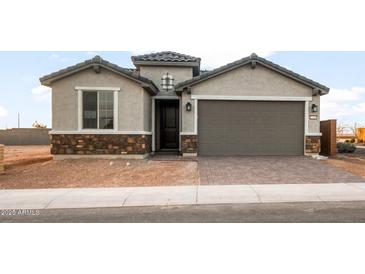 Inviting single-Gathering home showcases stone accents and a covered entryway leading to a spacious two-car garage at 27110 W Adam Ave, Buckeye, AZ 85396