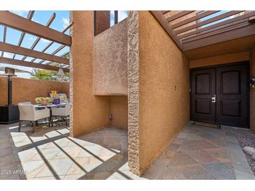 Inviting home entrance with rustic accents, stone-tiled floor, and outdoor dining area at 7401 N Scottsdale Rd # 24, Paradise Valley, AZ 85253
