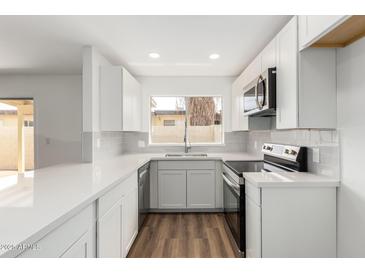 Bright kitchen with white cabinets, stainless steel appliances, and wood-look flooring at 747 W Rice Dr, Tempe, AZ 85283