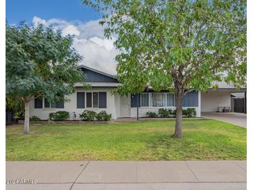 Charming single-story home with lush green lawn, mature trees, and covered carport at 2425 W Shady Glen Ave, Phoenix, AZ 85023