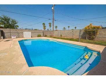 Sparkling in-ground pool surrounded by a concrete patio and secure fencing at 3736 W Hazelwood St, Phoenix, AZ 85019