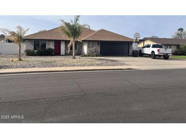 Charming single-story home features stone accents, well-maintained landscaping, and a convenient two-car garage at 5537 E Drummer Ave, Mesa, AZ 85206