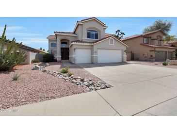 Two story home featuring a neutral color scheme, red roof, landscaping, and a spacious three car garage at 5959 W Lone Cactus Dr, Glendale, AZ 85308