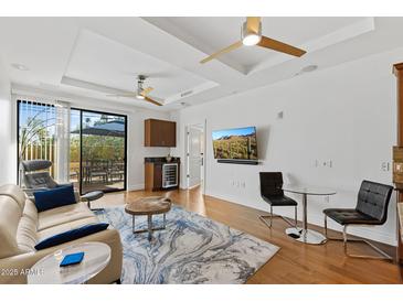 Bright living room features hardwood floors, ceiling fans, wet bar, and sliding glass door to balcony at 6803 E Main St # 1106, Scottsdale, AZ 85251