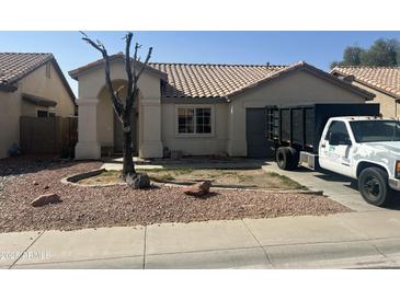 Beige single-story home featuring a red rock yard and a red tile roof and a trash truck parked on the right side at 8349 W Holly St, Phoenix, AZ 85037
