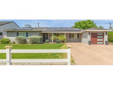 Charming single-story home with a well-manicured lawn, updated garage door, and solar panels at 4208 E Windsor Ave, Phoenix, AZ 85008