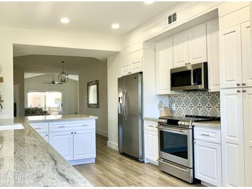 Bright kitchen with white cabinets, stainless steel appliances, and eye-catching backsplash detail at 8653 E Royal Palm Rd # 2010, Scottsdale, AZ 85258