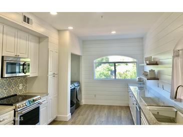 Bright kitchen features white cabinets, light countertops, stainless steel appliances, and an arched window at 8653 E Royal Palm Rd # 2010, Scottsdale, AZ 85258