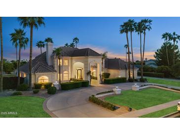 Elegant two-story home with a circular driveway and lush landscaping, accentuated by towering palm trees at 3943 E Laurel St, Mesa, AZ 85215