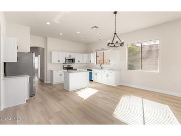Bright, open kitchen boasts white cabinets, island, and stainless steel appliances at 1112 E Winged Foot Dr, Chandler, AZ 85249