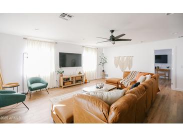 Open-concept living room featuring hardwood floors, a large sectional sofa, and plenty of natural light at 4025 N 8Th Ave, Phoenix, AZ 85013