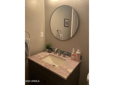 Bathroom vanity features a round mirror, granite countertop, and stylish faucet at 4242 N 27Th St # 2, Phoenix, AZ 85016