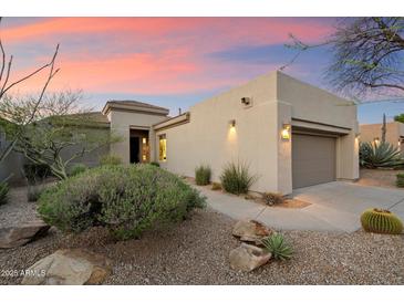 A home with desert landscaping featuring rocks, gravel, and green plants at 6522 E Night Glow Cir, Scottsdale, AZ 85266