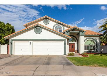 Charming home featuring a three-car garage, red tile roof, and lush green lawn at 844 W Sherri Dr, Gilbert, AZ 85233