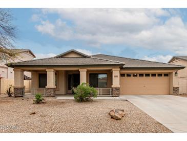 Charming home featuring a two-car garage, covered porch with stone accents, and desert landscaping at 16187 W Gibson Ln, Goodyear, AZ 85338