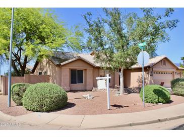 Charming single-story home featuring a well-maintained yard with desert landscaping and mature trees at 1624 E Marigold St, Casa Grande, AZ 85122