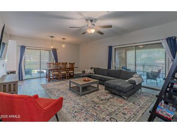 This living room features a ceiling fan, large sectional sofa, and sliding door to a balcony at 16801 N 94Th St # 1010, Scottsdale, AZ 85260