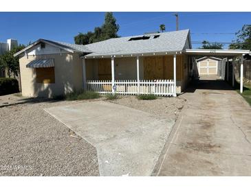 Single story home with boarded up windows, gravel landscaping, and a carport at 2230 N Laurel Ave, Phoenix, AZ 85007