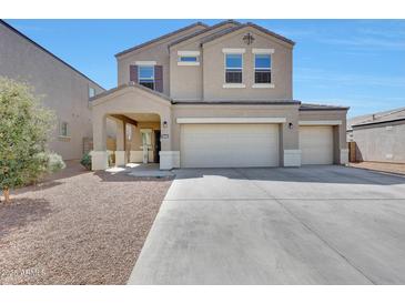 Two story home featuring a two-car garage, manicured landscaping, and a welcoming covered front porch at 30683 W Amelia Ave, Buckeye, AZ 85396