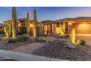 Inviting front entrance featuring desert landscaping, a stone gated entry, and warm exterior lighting at 41424 N Club Pointe Dr, Anthem, AZ 85086