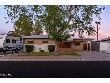 Charming single-story home featuring a covered porch and carport, complemented by mature landscaping and RV parking at 4527 N 12Th Ave, Phoenix, AZ 85013