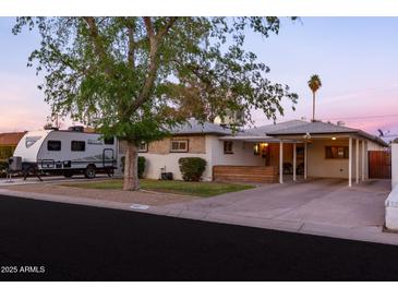 Charming single-story home featuring a covered porch and carport, complemented by mature landscaping and RV parking at 4527 N 12Th Ave, Phoenix, AZ 85013