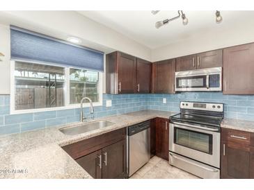 Updated kitchen features granite counters, stainless appliances, blue subway tile backsplash, and bright window at 6411 S El Camino Dr, Tempe, AZ 85283