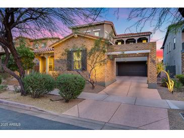 Charming brick home with a two-car garage and desert landscaping under a vibrant sunset sky at 9439 E Trailside Vw, Scottsdale, AZ 85255