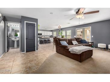 Comfortable living room featuring a plush brown sofa, ceiling fan, and tile flooring at 11737 W Robin Dr, Sun City, AZ 85373