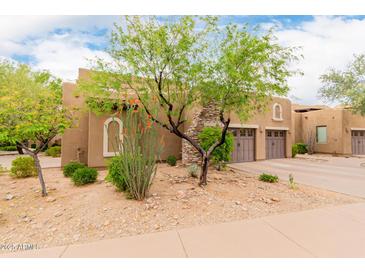 Neutral stucco exterior with stone accents, arched windows, mature trees, and manicured desert landscaping at 13300 E Via Linda -- # 1065, Scottsdale, AZ 85259