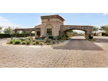 Elegant gated community entrance featuring stone archway, water fountain, and lush landscaping at 18502 N 98Th Way, Scottsdale, AZ 85255