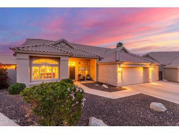 Charming single-story home featuring a well-manicured lawn and an attached two-car garage at twilight at 2040 E Indigo Brush Rd, Phoenix, AZ 85048