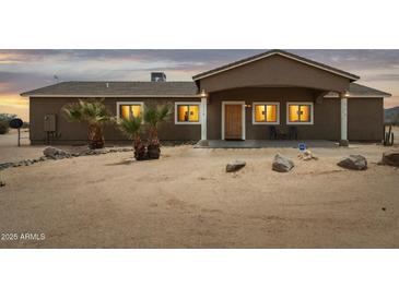 Charming single-story home featuring desert landscaping, a covered porch, and warm exterior lighting at 54463 W Sunburst St, Maricopa, AZ 85139