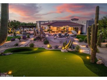Expansive backyard with putting green, pool, desert landscaping, and cozy outdoor living area at dusk at 7788 E Morning Vista Ln, Scottsdale, AZ 85266