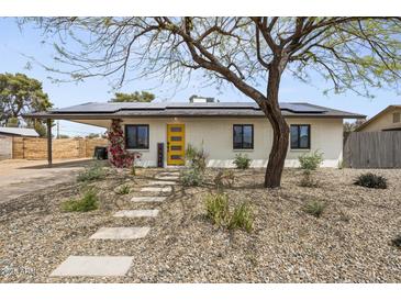 Charming home featuring solar panels, a bright yellow front door, and desert landscaping at 13419 N 35Th St, Phoenix, AZ 85032
