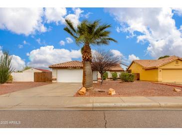 Charming home featuring a well-maintained front yard, a palm tree, and a two-car garage at 1414 W Grovers Ave, Phoenix, AZ 85023
