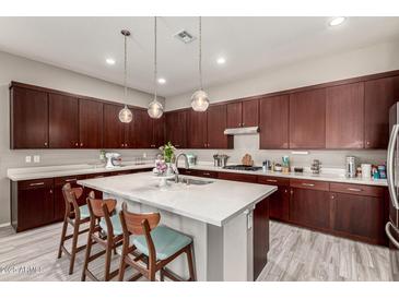 Spacious kitchen featuring an island, pendant lighting, and dark wood cabinets at 22434 S 226Th Pl, Queen Creek, AZ 85142