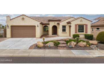 Charming, earth-toned home featuring a tile roof, arched entryway, and desert-friendly landscaping at 26190 W Siesta Ln, Buckeye, AZ 85396