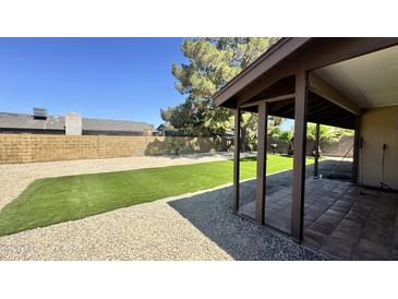 Serene backyard with artificial turf, gravel, and a covered patio for outdoor relaxation and enjoyment at 14017 N 40Th Ave, Phoenix, AZ 85053