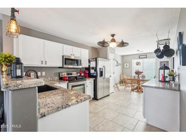 Bright kitchen featuring granite countertops, stainless steel appliances, and a view of the dining area at 15136 N 162Nd Ln, Surprise, AZ 85379