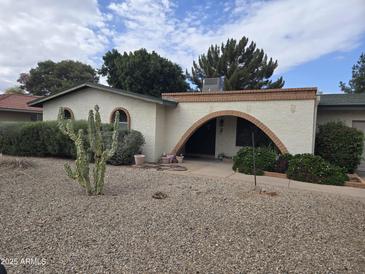 Charming single-story home featuring a desert landscape and unique arched doorway at 4718 W El Caminito Dr, Glendale, AZ 85302