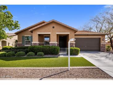 Charming single-story home featuring a well-manicured lawn, stone accents, and an attached two-car garage at 20181 N Lauren Rd, Maricopa, AZ 85138
