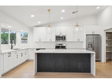 Bright kitchen features white cabinets, modern stainless-steel appliances, and pendant lighting at 3026 E Bremen St, Phoenix, AZ 85032