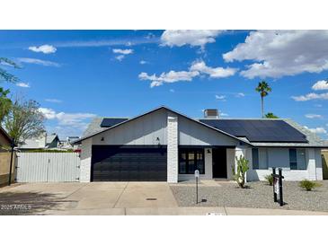 Charming single-story home showcasing a brick facade, modern garage door, and solar panels against a vibrant sky at 4038 W Windrose Dr, Phoenix, AZ 85029