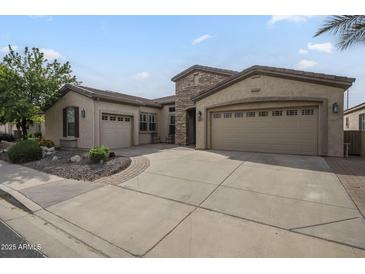 Inviting single-story home featuring a low-maintenance yard and a spacious driveway leading to a three-car garage at 4497 E Ficus Way, Gilbert, AZ 85298