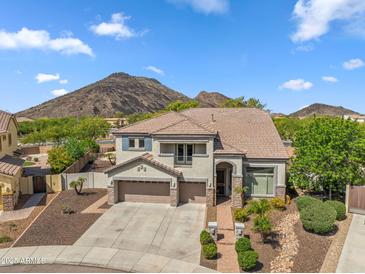 A tan, two story home with a three car garage, desert landscaping, and a mountain in the background at 5042 W Lariat Ln, Phoenix, AZ 85083