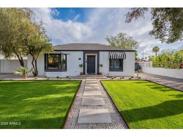 Charming single-story home with lush green lawn, stone pathway, and classic architectural details at 541 W Palm Ln, Phoenix, AZ 85003